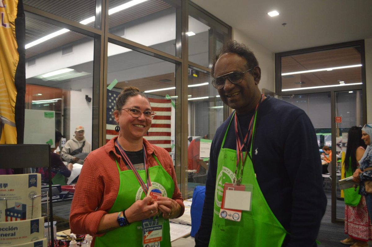 Lead Ravi Kumar and volunteer Gretchen Schwartz pose for a photo in front of the Cupertino Library vote center. Photo | Vaishnavi Katukam 
