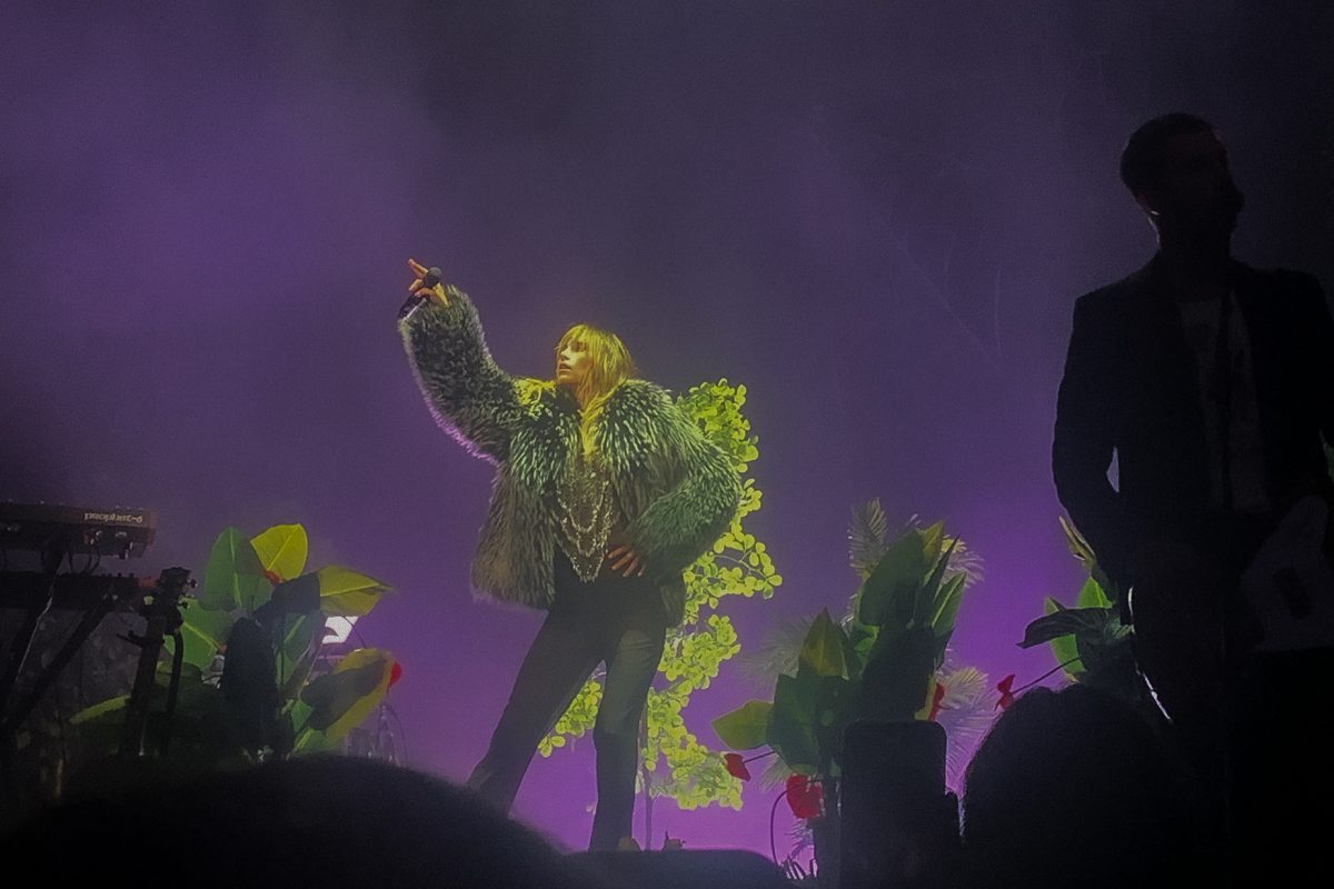 Surrounded by purple lights, Waterhouse points up, as the crowd cheers. 