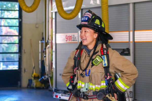 Firefighter engineer Ruri Kobayakawa dons her turnout gear as she converses with a colleague. Photo | Liz Liu
