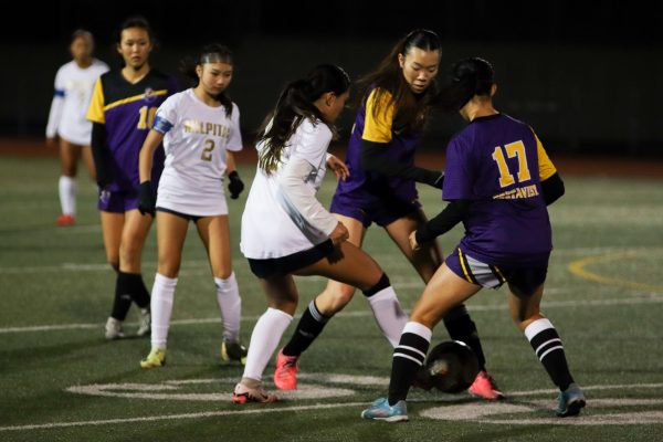 Senior and defensive midfielder Dylan Hwang and sophomore and defender Joyce Chou pressure a Milpitas player on opposite sides in an attempt to steal possession of the ball.