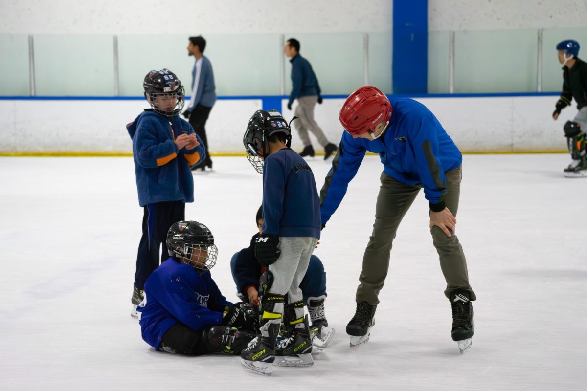 An adult helps up a fallen ice skater at Cupertino Ice Center. Photo | Alan Tai