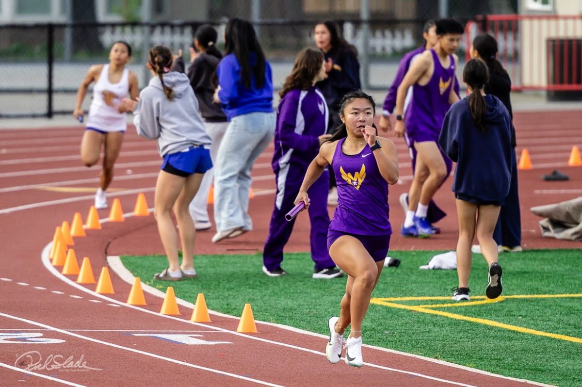 Senior Katie Lee holds the baton as she runs a relay race. Photo by Rich Slade | Used with permission