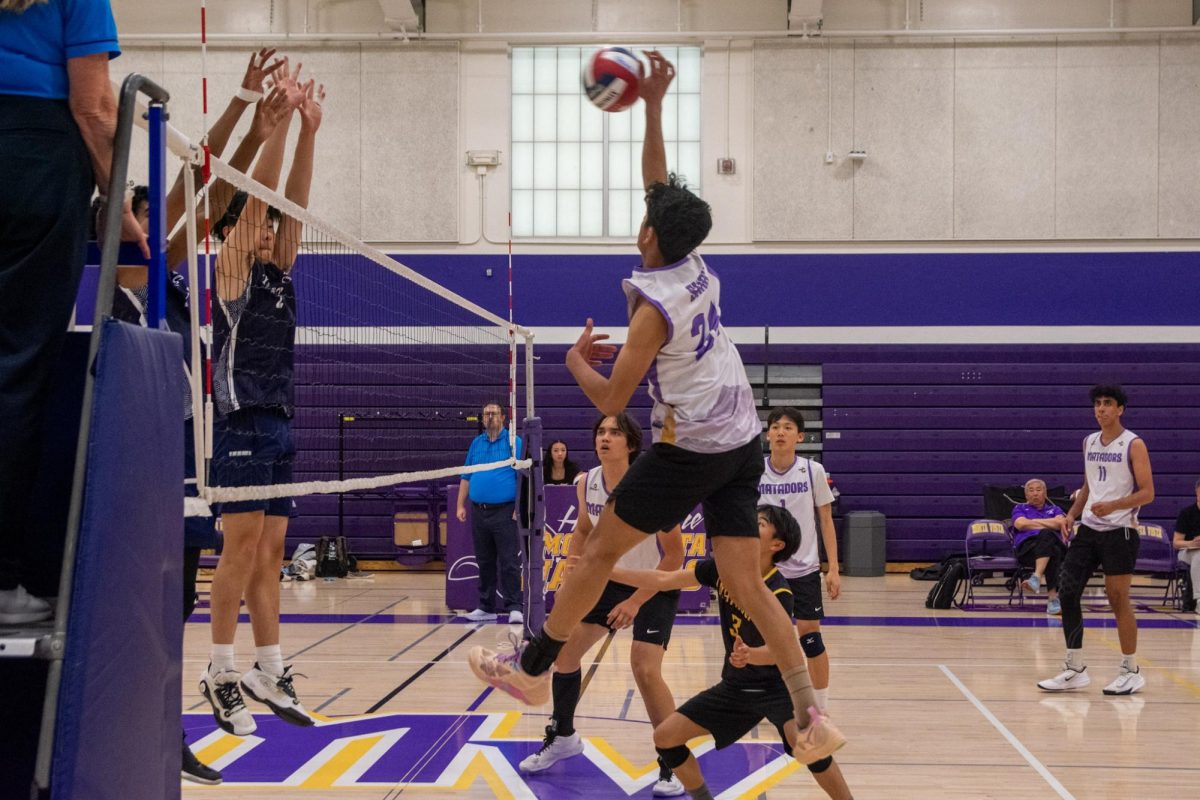 Senior and outside hitter Praneel Shah hits the ball over the net, attempting to avoid a block by LHS. Photo | Grace Lin
