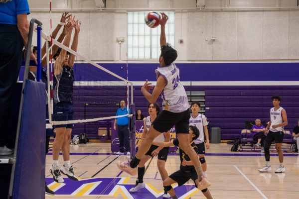 Senior and outside hitter Praneel Shah hits the ball over the net, attempting to avoid a block by LHS. Photo | Grace Lin
