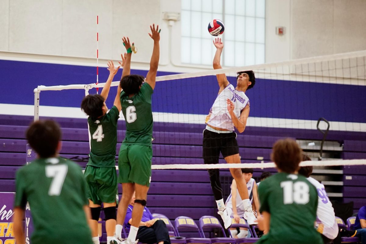 Junior and opposite hitter/middle blocker Pratham Kannan hits the ball past two Harker opponents. Photo | Ethan Yang