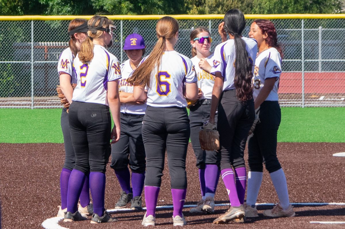 Varsity Softball huddles together at the pitcher’s mound before the game starts. Photo | Kaia Yuan