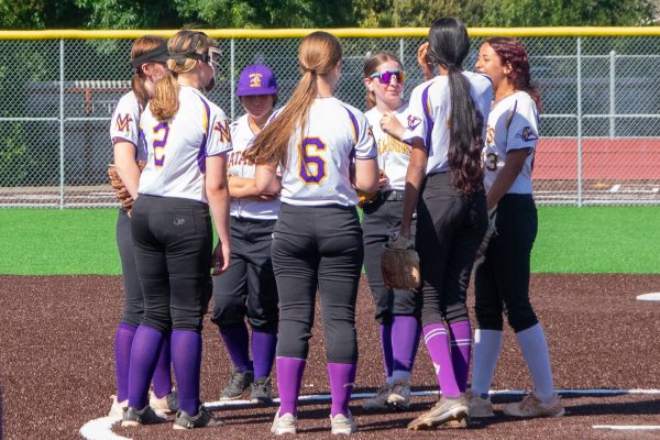 Varsity Softball huddles together at the pitcher’s mound before the game starts. Photo | Kaia Yuan