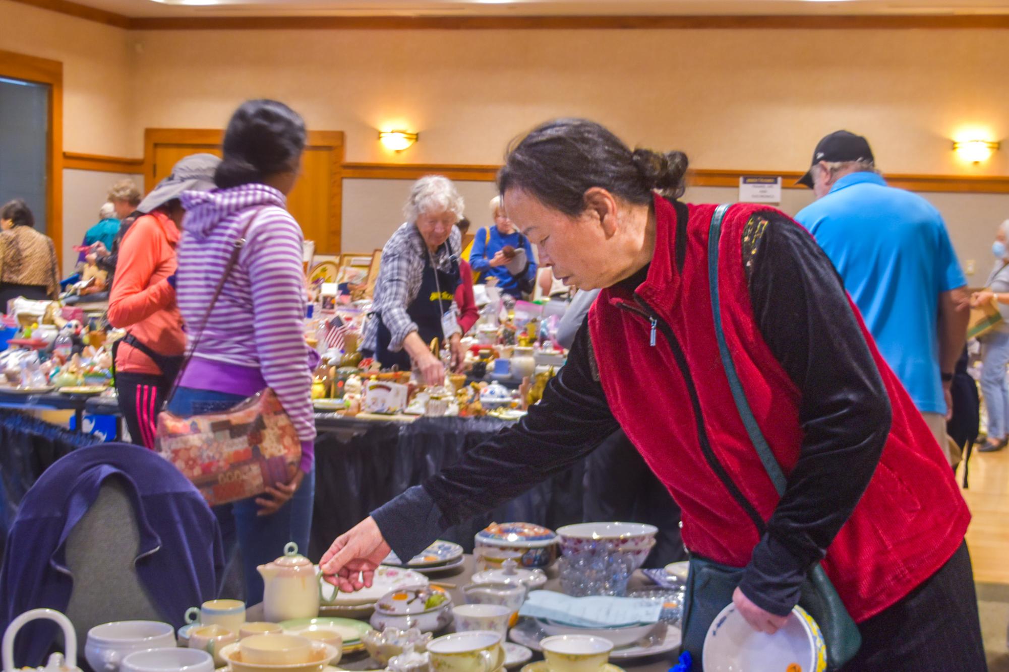 Examining a table of ceramic dinnerware, a shopper leans over to grab a small cup and check its price. Photo | Sana Karkhanis