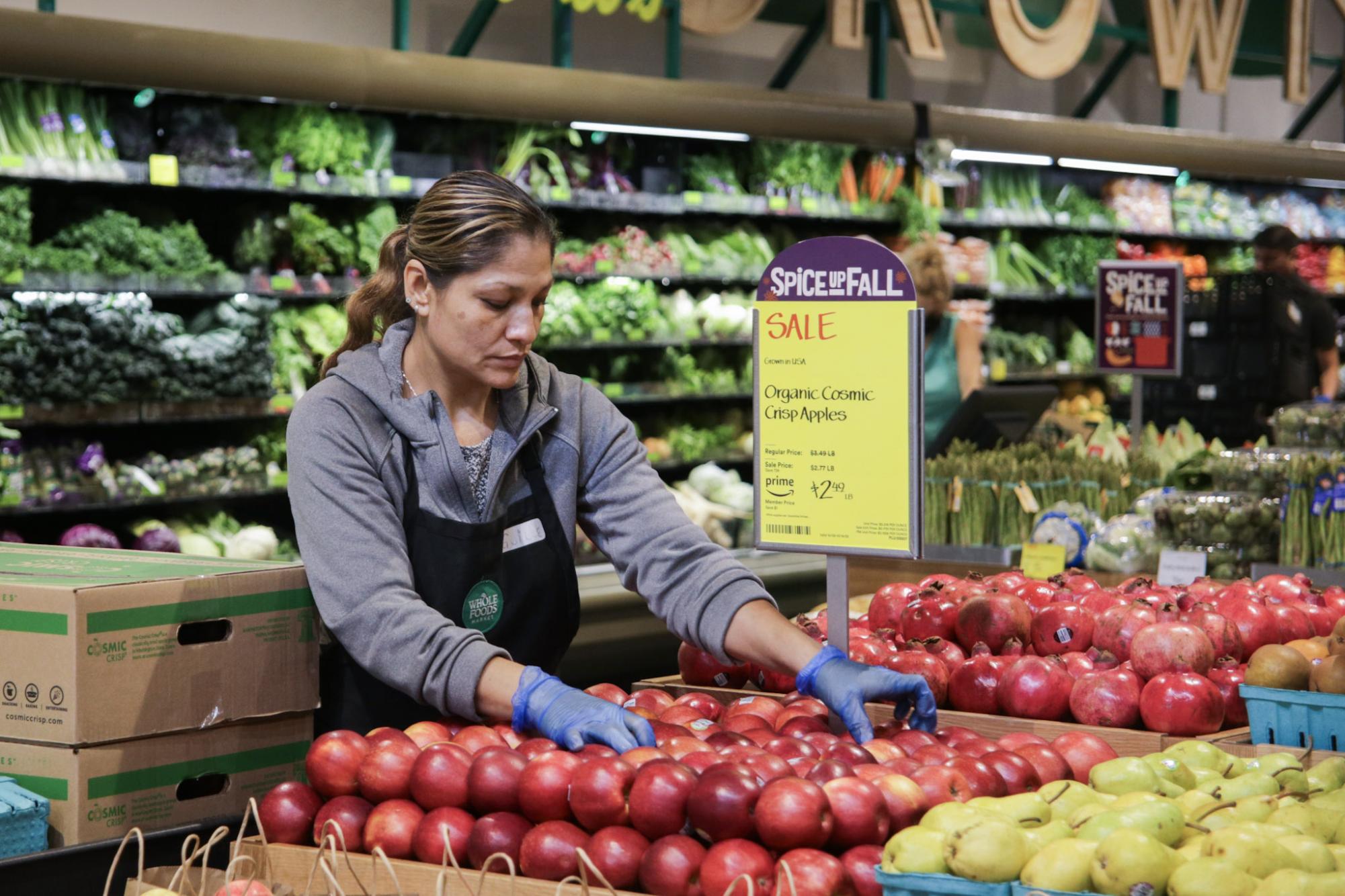 A Whole Foods worker arranges apples in the produce section. During the Stevens Creek store’s closure, areas holding fresh and perishable foods were completely removed and renovated.