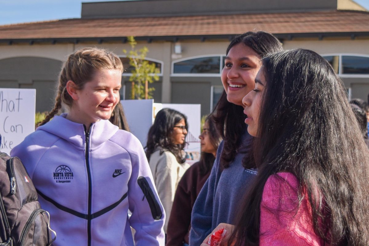 Junior Rachel Bergendahl chats with two students checking out the Nutrition Club poster board. Photo | Sophia D'Sa