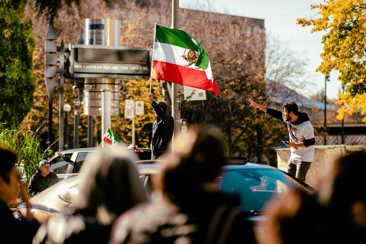  A group of protesters gathered while one person holds the Persian flag. Photo by Tianlei Wu| Used with permission