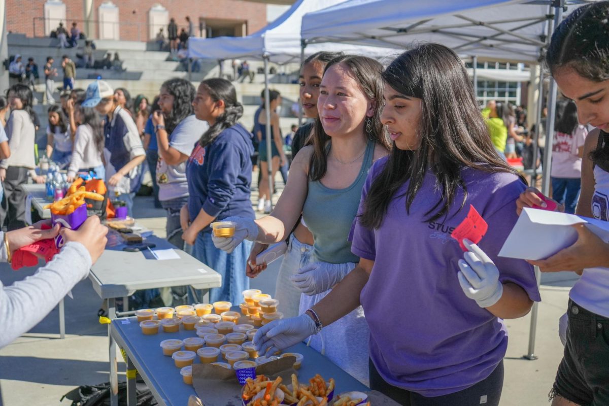 Sophomores Cynthia Hirano, Simran Mirchandani and Myra Mishra hand fries and sauce from Taco Bell to student customers during Club Grub Day. Photo | Ellie Wang