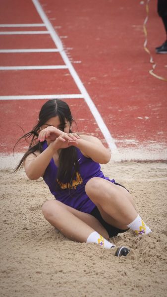 Lauren Moore finishes her triple jump trial, landing in the sandpit, during a meet | Photo courtesy of Lauren Moore