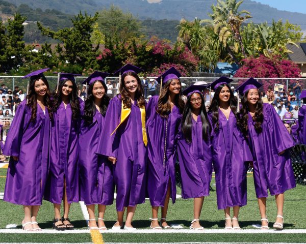 Decked in purple, seniors Courtney Masli, Trisha Mahajan, Emily Lin, Nicole Jeleva, Leah Desai, Anvika Verma, Alaina Agarwal and Miya Sakurai (left to right) smile towards the crowd as their parents take pictures of them. Photo | Emmy Harimoto